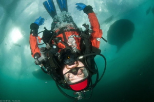 upside down diver walking under ice by Mathieu Foulquié 
